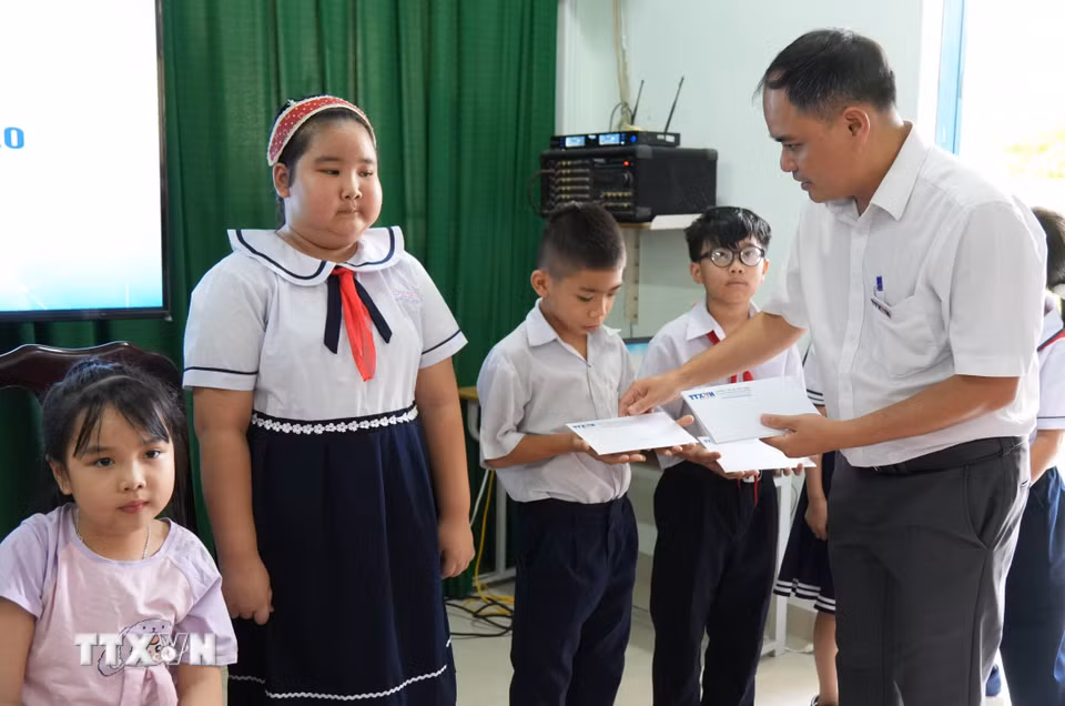 Trưởng Cơ quan thường trú TTXVN tại Khánh Hòa Vũ Xuân Triệu tặng học bổng cho học sinh có hoàn cảnh khó khăn của trường Tiểu học Tây Nha Trang. (Ảnh: Nguyễn Dũng/TTXVN)