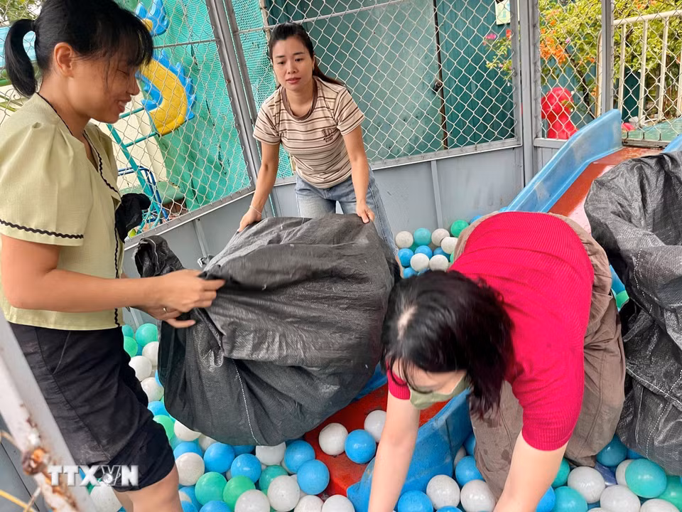 Giáo viên trường Mầm non Xuân Mai (xã Xuân Mai, Hà Nội) thu dọn đồ chơi, tránh nước ngập. (Ảnh: TTXVN phát)