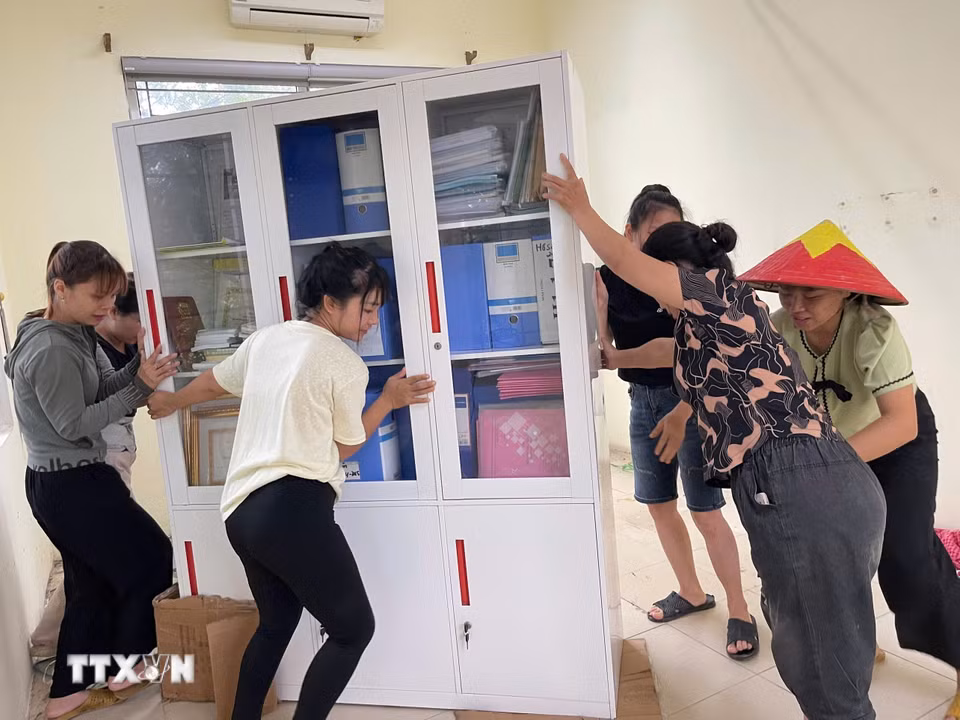 Người dân hỗ trợ di dời tài sản của trường Mầm non Xuân Mai (xã Xuân Mai, Hà Nội) lên cao tránh nước ngập. (Ảnh: TTXVN phát)