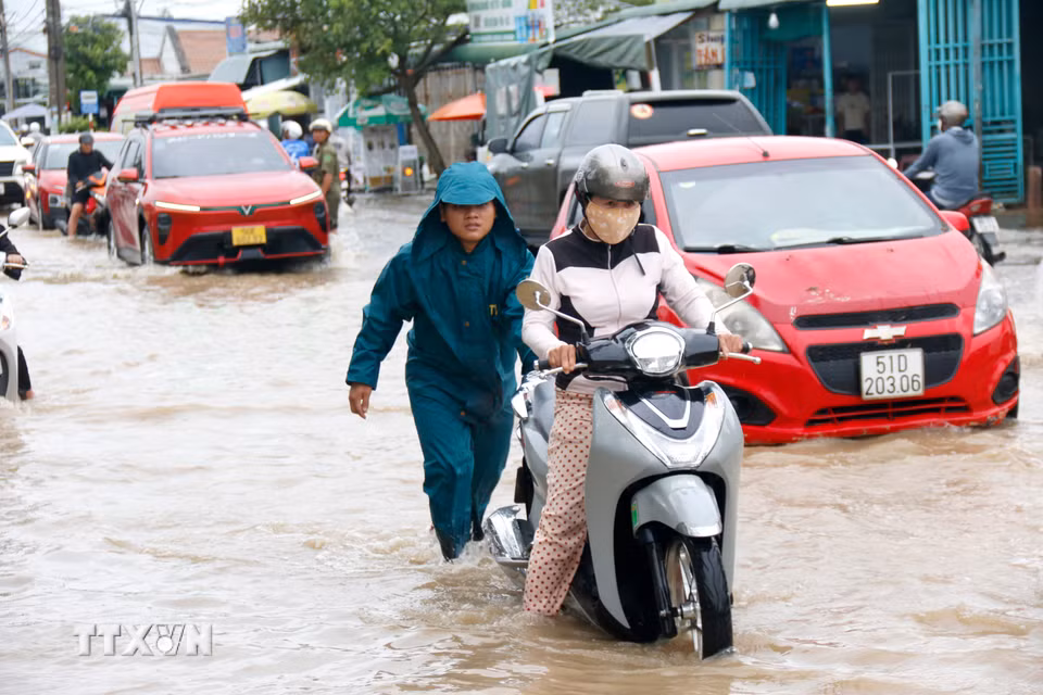 Lực lượng chức năng được bố trí hỗ trợ người dân di chuyển qua đoạn ngập sâu trên quốc lộ 28 qua phường Hàm Thắng. (Ảnh: Nguyễn Thanh/TTXVN) ​