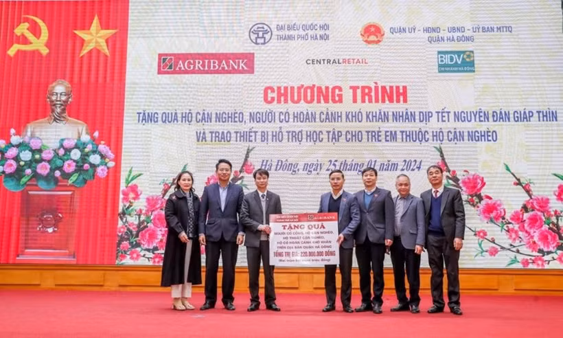 Ông Phạm Đức Ấn - Chủ tịch Hội đồng thành viên Agribank trao tặng quà của Agribank hỗ trợ hộ cận nghèo, đối tượng chính sách quận Hà Đông (Hà Nội) nhân dịp Tết Nguyên đán Giáp Thìn. (Ảnh: Vietnam+)