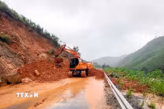Lực lượng chức năng thu dọn đất đá sạt lở. (Ảnh: Phạm Lợi/TTXVN)