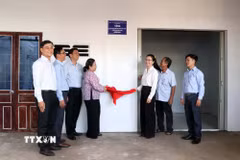 Lãnh đạo thành phố Cần Thơ và chính quyền địa phương thực hiện tháo khăn, gắn biển bàn giao nhà mới cho gia đình bà Võ Thị Liến. (Ảnh: Trung Kiên/TTXVN)