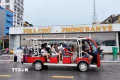 Các du khách đi xe điện ra cảng tàu để lên tàu trở về đất liền. (Ảnh: Thu Báu/TTXVN phát)