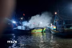 Lực lượng chức năng hỗ trợ chữa cháy tàu cá BTh 89330 TS (công suất 40CV, dài 10m). (Ảnh: Nguyễn Thanh/TTXVN)
