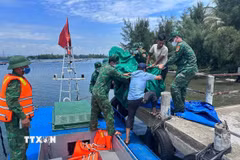 Cán bộ chiến sỹ Đồn biên phòng Tam Thanh chuyển thi thể nạn nhân vào đất liền. (Ảnh: TTXVN phát)