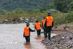 Các lực lượng chức năng, chính quyền địa phương và người dân xã Dân Hoá đang triển khai tìm kiếm người phụ nữ bị mất tích. (Ảnh: TTXVN phát)