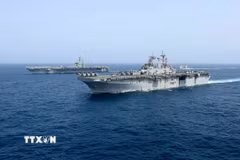 Tàu sân bay USS Abraham Lincoln (phía sau) của hải quân Mỹ di chuyển trên Biển Arab. (Ảnh minh họa: AP/TTXVN)