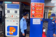 Lực lượng quản lý thị trường triển khai dán thông báo số điện thoại đường dây nóng, tại các cửa hàng xăng, dầu. (Ảnh: Trần Tĩnh/TTXVN)