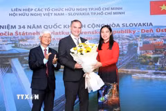 Bà Hà Thanh, Chủ tịch Liên hiệp các tổ chức hữu nghị Thành phố Hồ Chí Minh và ông Bùi Quang Hải, Chủ tịch Hội Hữu nghị Việt Nam-Slovakia Thành phố Hồ Chí Minh tặng hoa chúc mừng ông Marian Veres, Đại biện lâm thời của Đại sứ quán Cộng hòa Slovakia tại Việt Nam. (Ảnh: Xuân Khu/TTXVN)