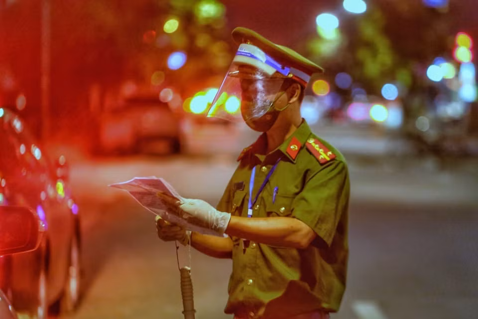 Lực lượng chức năng kiểm tra giấy tờ người đi đường tại chốt kiểm soát phố Huế. (Ảnh: Tuấn Đức/TTXVN)