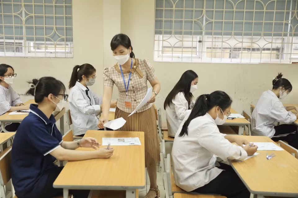 Giám thị phát giấy thi cho thí sinh tại điểm thi trường THPT Nguyễn Gia Thiều, quận Long Biên, thành phố Hà Nội. (Ảnh: Minh Quyết/TTXVN)