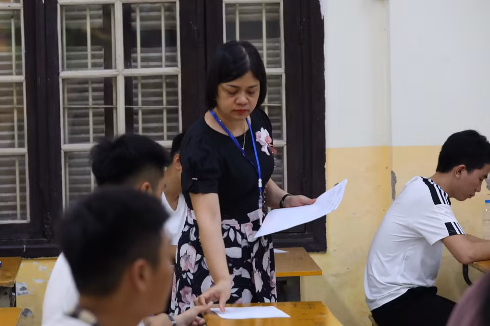 Giám thị phát giấy nháp cho thí sinh điểm thi Trường THPT Phan Đình Phùng, quận Ba Đình, Hà Nội. (Ảnh: Hoàng Hiếu/TTXVN)
