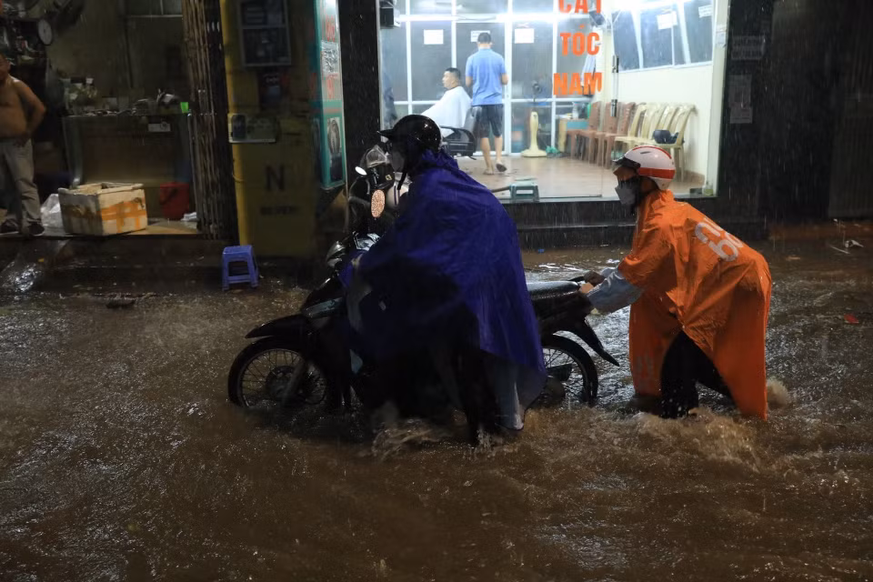 Nhiều người phải đẩy xe đi qua chỗ ngập trên phố Khương Hạ, quận Thanh Xuân. (Ảnh: Tuấn Anh/TTXVN)