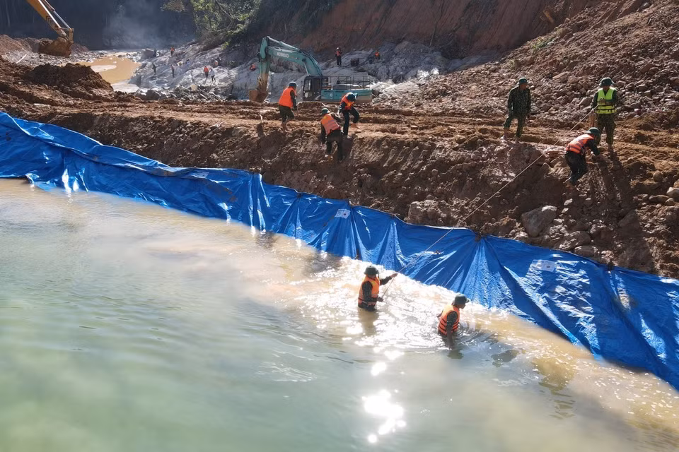Lực lượng chức năng nắm dòng chảy mới được tạo nên để phục vụ công tác tìm kiếm dưới lòng suối Rào Trăng. (Ảnh: TTXVN phát)