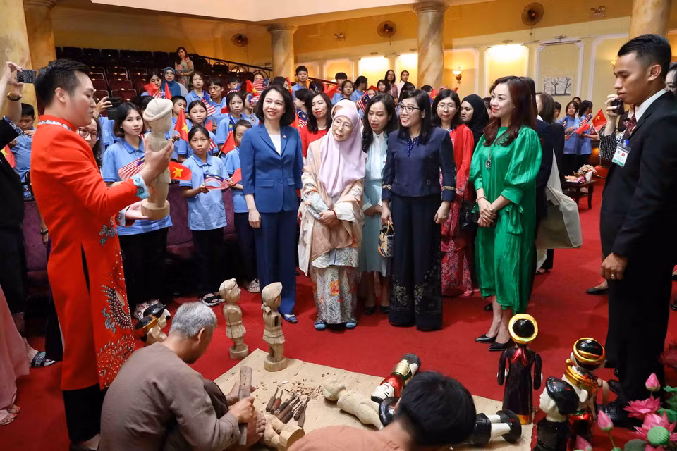 Phu nhân Thủ tướng Việt Nam Lê Thị Bích Trân và Phu nhân Thủ tướng Malaysia Dato' Seri Dr. Wan Azizah binti Dr. Wan Ismail nghe giới thiệu công việc tạo hình quân rối nước của các nghệ nhân. (Ảnh: Phạm Kiên/TTXVN)