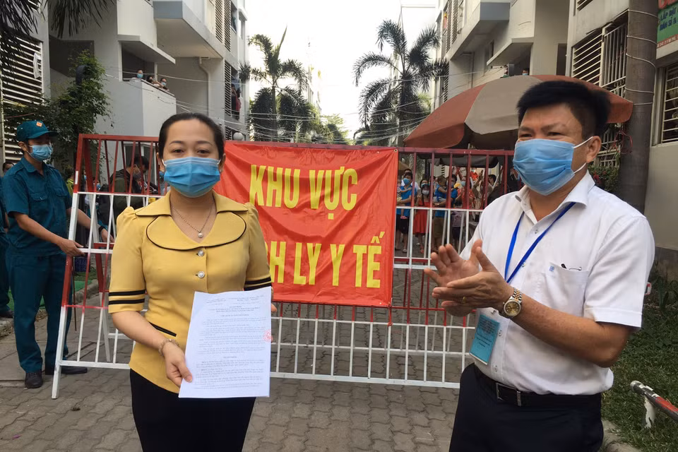 Lãnh đạo Ủy ban nhân dân phường Vĩnh Phú công bố quyết định dỡ bỏ phong tỏa khu C2, Khu dân cư Ehome4. (Ảnh: Văn Hướng/TTXVN)