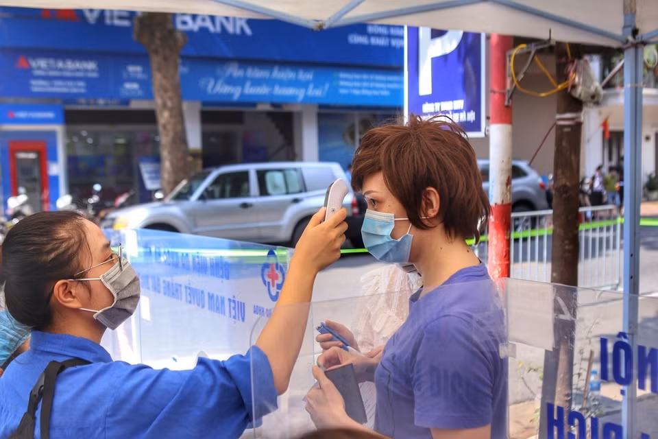 Đo thân nhiệt cho người dân đến tiêm tại điểm tiêm Bệnh viện Đa khoa Hà Nội (chiều 9/9). (Ảnh: Tuấn Đức/TTXVN)