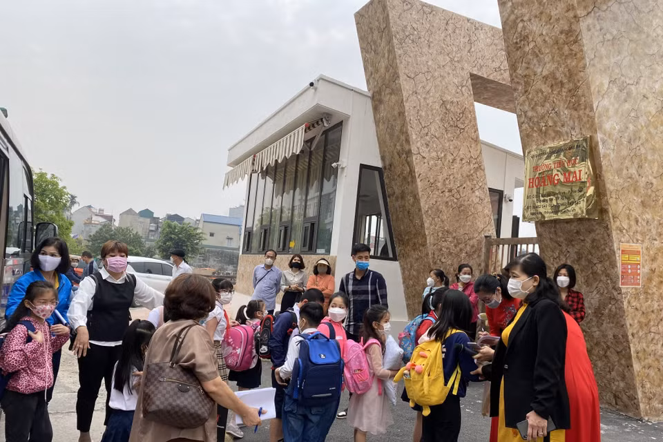 Tại trường Tiểu học Hoàng Mai, Ban giám hiệu, giáo viên trong tà áo dài truyền thống có mặt ở cổng trường từ rất sớm đón các con lần đầu tiên tới ngôi trường mới. Hiệu trưởng nhà trường cho biết đã cố gắng bố trí cho các con học bán trú để cha mẹ có thể yên tâm làm việc. (Ảnh: PV/Vietnam+)
