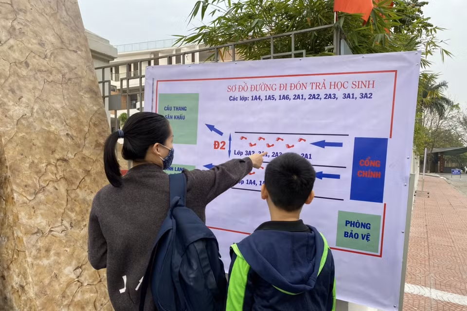 Các lối đi đón, trả học sinh tại Trường Tiểu học Hoàng Mai đều được phân luồng rõ ràng tránh tụ tập đông người. Trong ảnh, một phụ huynh dặn dò con lối đi để thực hiện nội quy của nhà trường. (Ảnh: PV/Vietnam+)