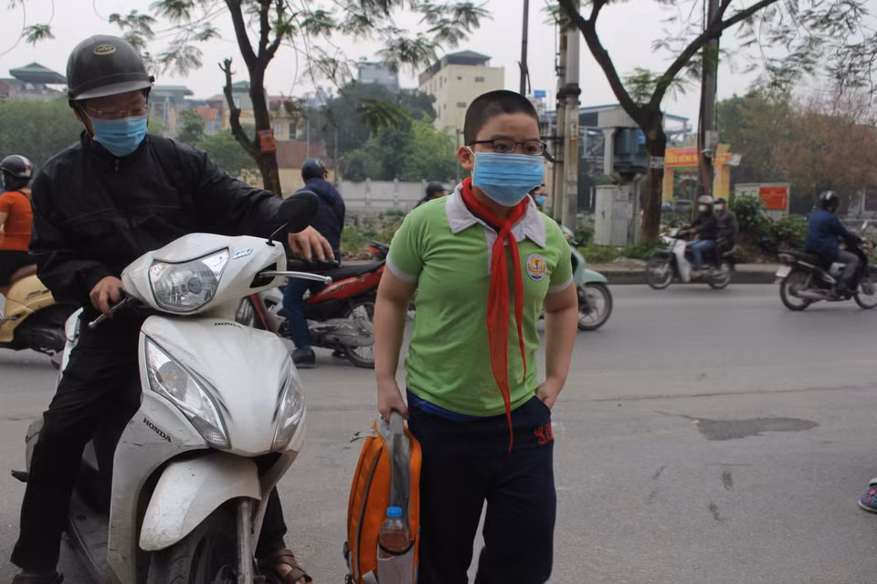 Tại cổng trường tiểu học Phạm Tu, anh Võ Thành Nam đã dặn dò con trai hạn chế tối đa bỏ khẩu trang, lưu ý khử khuẩn tay và các công tác chống dịch theo khuyến cáo của nhà trường. (Ảnh: Minh Anh/Vietnam+)