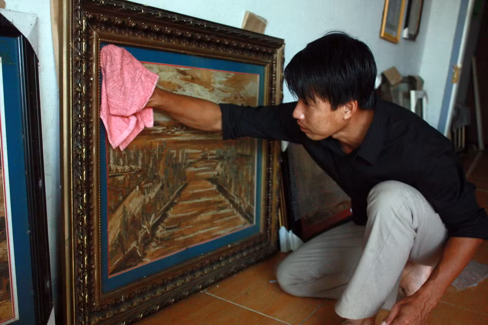 Anh Lê Hoàng Nhân với một tác phẩm tranh vỏ tràm hoàn chỉnh vừa mới hoàn thành. (Ảnh: Lê Sen/TTXVN)