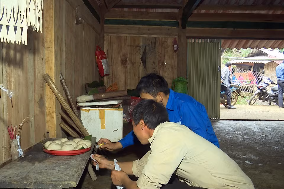 Nghi thức dán giấy lên các công cụ lao động và đồ dùng của người Mông. Ảnh: Hữu Quyết/TTXVN)