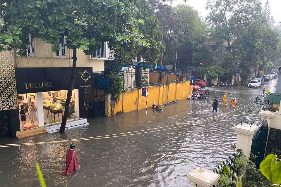 Người dân phải lội bì bõm trong dòng nước bẩn. (Ảnh: Vietnam+)
