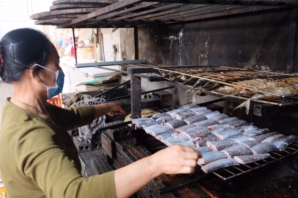 Đưa cá lên giàn nướng than. (Ảnh: TTXVN phát)