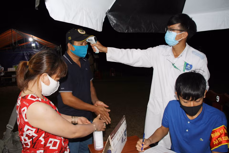 Người dân được sát khuẩn tay và kiểm tra thân nhiệt tại chốt kiểm dịch trên đường Hồ Chí Minh, xã Hòa Phú, thành phố Buôn Ma Thuột, tỉnh Đắk Lắk. (Ảnh: Tuấn Anh/TTXVN)