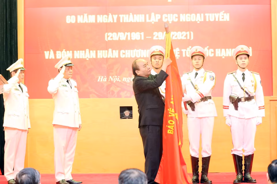 Chủ tịch nước Nguyễn Xuân Phúc gắn Huân chương Bảo vệ Tổ quốc hạng Nhì lên cờ truyền thống của Cục Ngoại tuyến. (Ảnh: Phạm Kiên/TTXVN)
