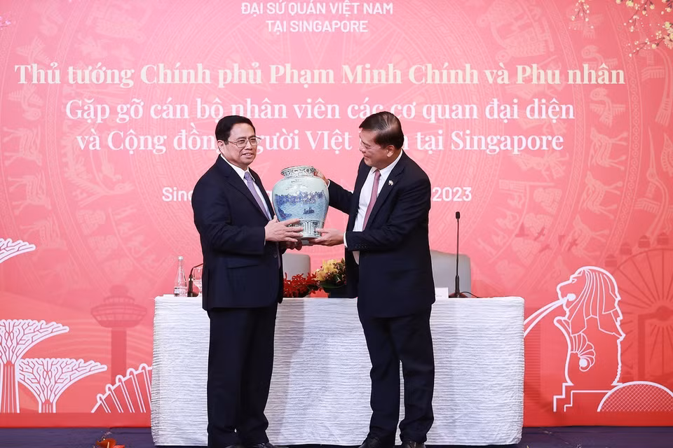 Thủ tướng Phạm Minh Chính tặng quà cho đại diện cán bộ, nhân viên các cơ quan đại diện Việt Nam tại Singapore. (Ảnh: Dương Giang/TTXVN)