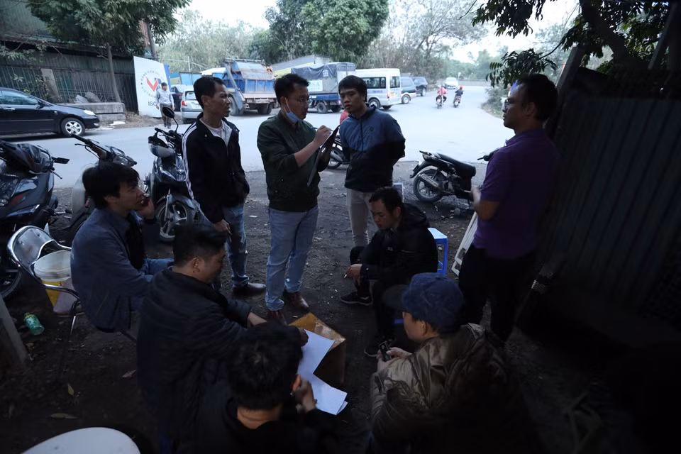 Lúc 17h30 ngày 12/1, các lái xe (nhiều người đến từ ngày 11/1) dàn xếp đồng thuận để xếp số theo thứ tự sáng 13/1. (Ảnh: Hoàng Hiếu/TTXVN)