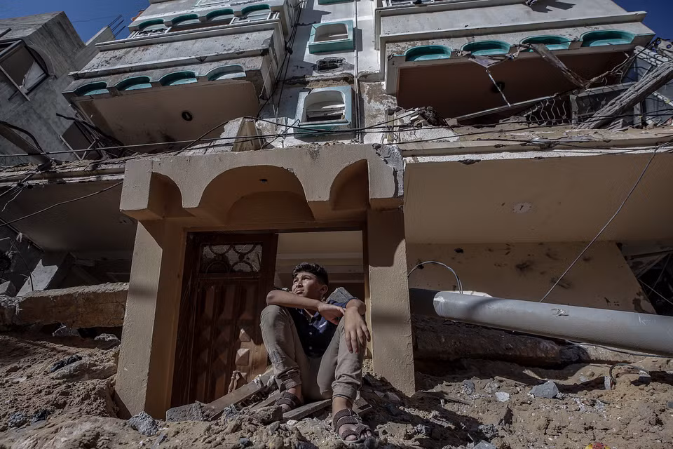 Một cậu bé người Palestine ngồi trên đống đổ nát của ngôi nhà bị phá hủy sau cuộc không kích của Israel ở thành phố Gaza. (Ảnh: EPA)