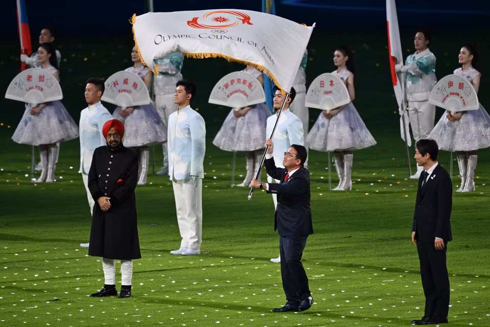 Đại diện của Nhật Bản (giữa) - chủ nhà ASIAD 20 - nhận chuyển giao lá cờ của Ủy ban Olympic châu Á (OCA) tại Lễ Bế mạc. (Ảnh: AFP/TTXVN)