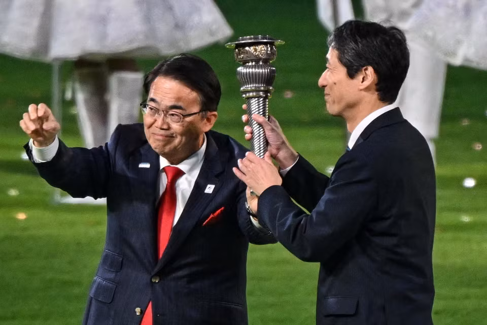 Đại diện của Nhật Bản - chủ nhà ASIAD 20 - nhận chuyển giao ngọn đuốc tại Lễ Bế mạc. (Ảnh: AFP/TTXVN)