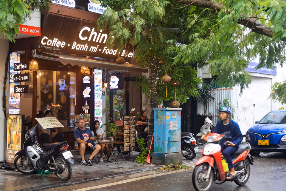 Một cơ sở kinh doanh dịch vụ tại số 61 Hàng Điếu (Cửa Đông, Hoàn Kiếm, Hà Nội) vẫn bày bàn ghế ra vỉa hè cho du khách nước ngoài ngồi dưới cây đang đổ. (Ảnh: Hoài Nam/Vietnam+)