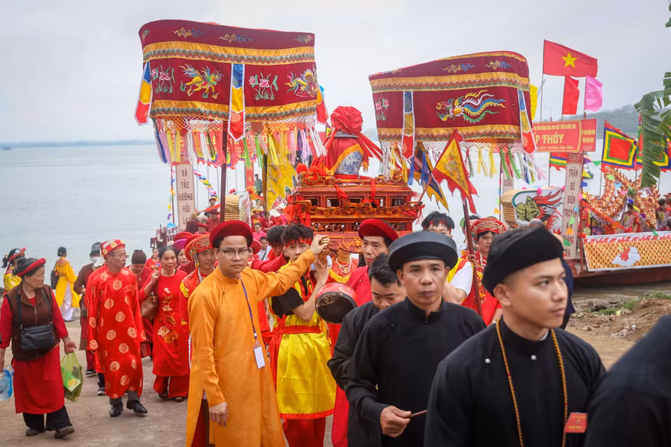Hoàn thành nghi thức lấy nước, đoàn rước lại trở về Đền thờ các vị vua Trần. Về tới sân Đền, đoàn rước lần lượt đi vào hành lễ, đoàn kiệu do các thanh niên trai tráng rước qua cổng là bắt đầu quay đủ ba vòng rồi đi vòng vào Đền. (Ảnh: Hoài Nam/Vietnam+)