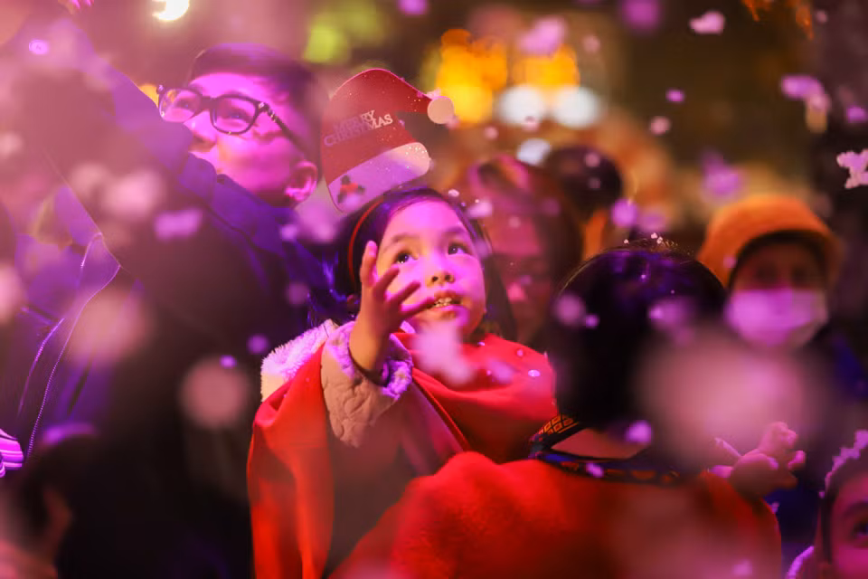 Nhiều bạn nhỏ rất thích thú với trải nghiệm này. Không khí lạnh giá tại Hà Nội thời điểm này cùng với "cơn mưa tuyết" tạo nên một Giáng sinh như ở trời Tây. (Ảnh: Hoài Nam/Vietnam+)