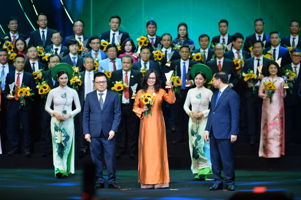Phó Thủ tướng Chính phủ, Bộ trưởng Ngoại giao Bùi Thanh Sơn và Tổng Biên tập Báo Nhân Dân, Chủ tịch Hội Nhà báo Việt Nam Lê Quốc Minh trao biểu trưng và hoa cho đại diện các doanh nghiệp. (Ảnh: Hoài Nam/Vietnam+)