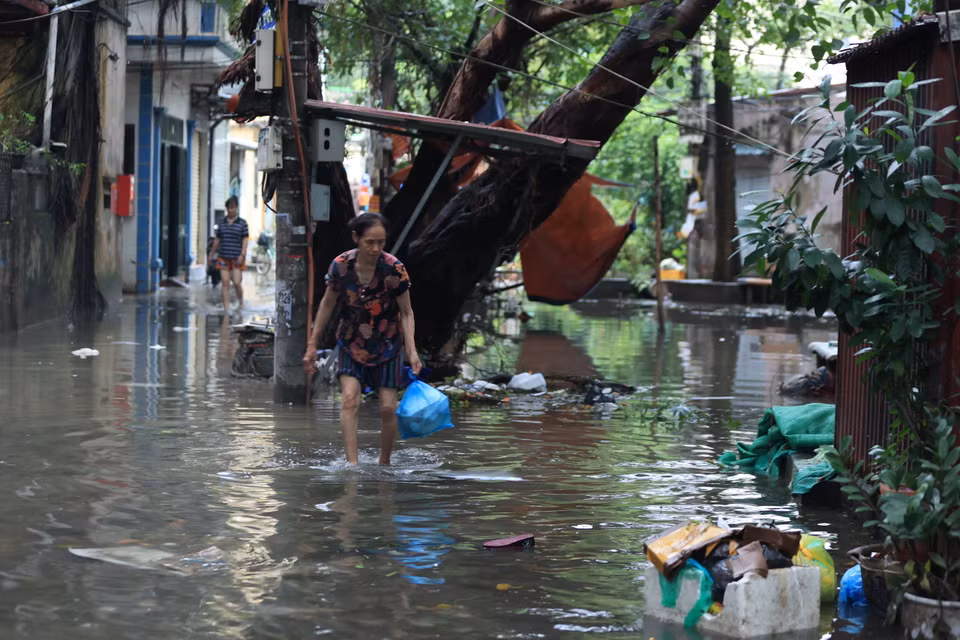 Người dân 'bì bõm' dọn rác sau cơn bão. (Ảnh: Hoài Nam/Vietnam+)