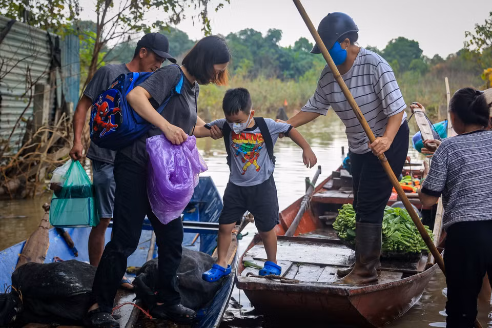 Chị Hà cho biết ngày trước cho con đi học mất 15-20 phút nhưng giờ gia đình phải dậy trước cả tiếng để di chuyển bằng thuyền trên con đường độc đạo từ bãi giữa về ngõ 76 An Dương đang chìm trong dòng nước. (Ảnh: Hoài Nam/Vietnam+)