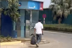 Người dân quay lại cảnh nghi phạm xách túi đựng tiền đi bộ ra ngoài.