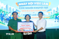 Đại diện các đơn vị, tổ chức tặng quà cho người khuyết tật tại Ngày hội việc làm. (Ảnh: Thanh Vũ/TTXVN)