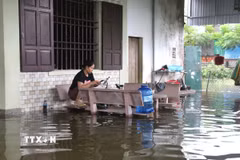 Nước ngập sâu vào hiên nhà, sinh hoạt của người dân gặp nhiều khó khăn. (Ảnh: Xuân Tiến/TTXVN)