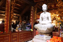 Người dân chiêm bái tượng Phật A Di Đà - Bảo vật Quốc gia bằng đá ở chùa Phật Tích. (Ảnh: Thanh Thương/TTXVN)