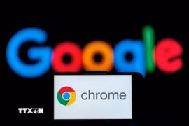 Biểu tượng Chrome trên màn hình điện thoại và biểu tượng Google (phía sau). (Ảnh: Getty Images/TTXVN)