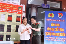 Tình nguyện viên Đội hình tình nguyện Công an tỉnh Đắk Lắk hỗ trợ người dân thực hiện thủ tục hành chính và thao tác cơ bản trên thiết bị điện thoại. (Ảnh: Hoài Thu/TTXVN)