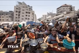 Người dân nhận thức ăn cứu trợ tại Dải Gaza. (Ảnh: IRNA/TTXVN)