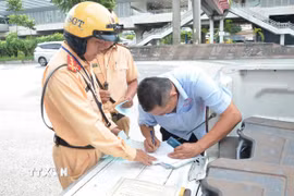 Cảnh sát giao thông lập biên bản một trường hợp tài xế xe khách vi phạm. (Ảnh: Linh Sơn/TTXVN)